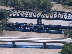 Crews work at the scene of a rail bridge collapse and railcars derailment over the Bow River, southeast of downtown Calgary, Alberta on Thursday, June 27, 2013.