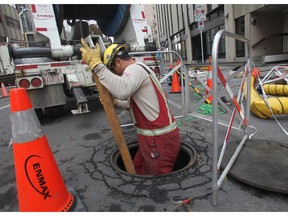 An Enmax lineman descends into the infamous manhole on 8th Street SW to replace cable burned by the October fire.