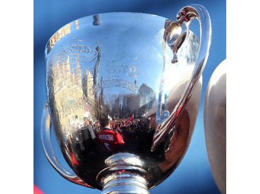 Jon Cornish, right, is reflected in the Grey Cup during the Grey Cup Champions rally at City Hall in Calgary on December 02, 2014.