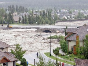 A major roadway disappears into the raging water as Canmore homes along Cougar Creek barely hang on during massive flooding Thursday, June 20.