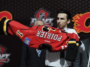 Emile Poirier, a winger, pulls on a Calgary Flames sweater after being chosen 22nd overall in the first round of the 2013 NHL hockey draft.