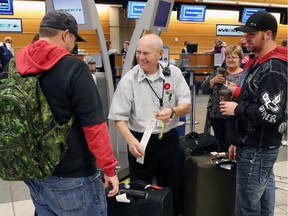 A WestJet employee helps passengers  check in at the Calgary International Airport on Oct. 30, 2014.