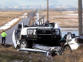 An RCMP officer takes measurements at the scene of a serious 2 vehicle crash on Township Road 254, Country Hills Boulevard, and the Conrich Road Friday morning December 12, 2014.