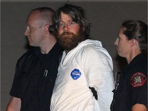 Trevor Kloschinsky is escorted by Calgary police at the CPS district 8 headquarters in southwest Calgary, Alberta early Saturday, August 11, 2012.