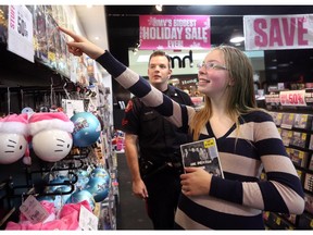 Genna Burnside, 14, from Bob Edwards School, rewards Const. Cory O'Reilly with a smile after finding a CD by her favourite band One Direction to buy. The two were teamed up Dec. 10, 2014, during the 8th annual CopShop at Marlborough Mall. The experience helps with positive relationships between youth at risk and CPS officers.
