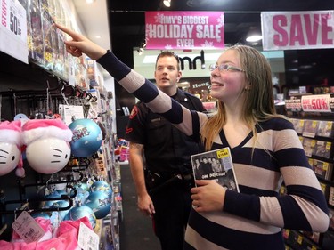 Genna Burnside, 14, from Bob Edwards School rewards Constable Cory O'Reilly with a smile after finding her favourite  CD band "One Direction" to buy. The two were teamed up during the 8th annual CopShop at Marlborough Mall. The experience helps with positive relationships between youth at risk and CPS officers on December 10, 2014.