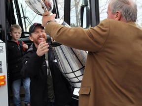 Calgary Stampeders head coach/GM John Hufnagel hands off the Grey Cup to  Dave Dickenson as the offensive co-ordinator's son Cooper looks on upon the Grey Cup-champion Stampeders' return to Calgary on Monday. On Wednesday, Huff announced plans to coach in 2015 before handing off the job to Dickenson in 2016.