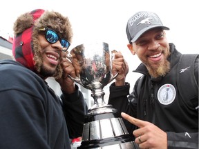 Receiver Nik Lewis, left, and linebacker Juwan Simpson lift the Grey Cup as the champion Stampeders return to Calgary on Monday.