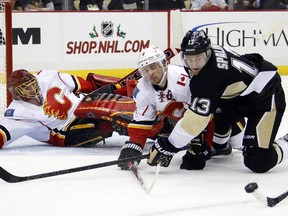 Pittsburgh Penguins' Nick Spaling (13) and Calgary Flames' Kris Russell (4) collide in front of Flames goalie Jonas Hiller (1) during the second period of an NHL hockey game in Pittsburgh, Friday, Dec. 12, 2014.(AP Photo/Gene J. Puskar)