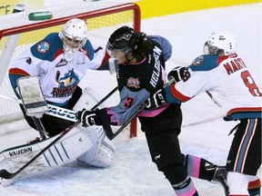 Calgary Hitmen's Kenton Helgesen and Kelowna Rockets' Cole Martin wrestle for position in front of Rockets goaltender Jackson Whistle during the first period on Sunday.