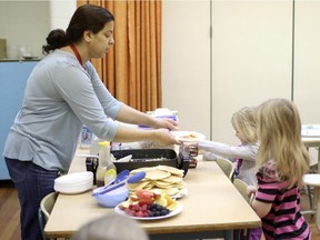 Mejally Enas, left, serves breakfast to students at Penbrooke Meadows School in Calgary on December 03, 2014. The Boys & Girls Clubs of Calgary supports the program for hungry kids in 180 schools across the city.