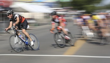 Independent racer Joshua Kutryk, left, leads round a high-speed tight corner at the Tour de Bowness bike race in Calgary, on August 4, 2014. The Criterium is a speed race on a short circuit street track, in which riders reach speeds up to 70 km/hr.