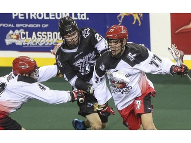 Calgary Roughnecks' Dane Dobbie, left, helps out teammate Jeff Shattler, right, by blocking Edmonton Rush player Ryan Dilks during exhibition game action at the Saddledome in Calgary, on December 20, 2014.