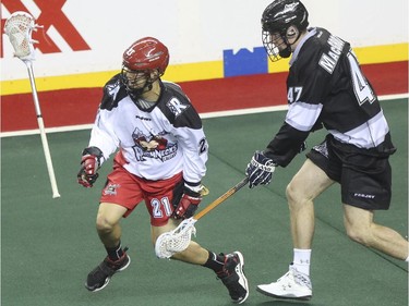 Calgary Roughnecks' Karsen Leung takes a lacrosse stick whack to the leg from Edmonton Rush's Matt MacGrottty during exhibition game action at the Saddledome in Calgary, on December 20, 2014.