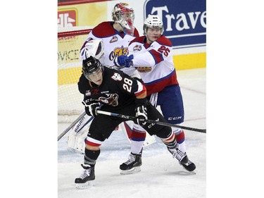 Calgary Hitmen left winger Elliott Peterson, left, was hassled outside the Edmonton Oil Kings crease centre Lane Bauer during first period WHL action at the Scotiabank Saddledome on December 17, 2014.