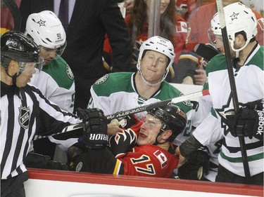 Lance Bouma of the Calgary Flames lands on the laps of Cody Eakin, centre, alongside Tyler Seguin, left, and Jason Demers, 4, after getting knocked into the bench during the second period at the Saddledome Friday night December 19, 2014.