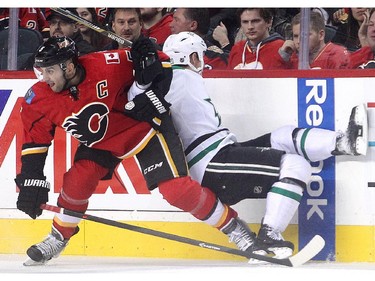 Calgary Flames captain Mark Giordano takes Cody Eakin of the Dallas Stars into the boards during the first period at the Saddledome Friday night December 19, 2014.