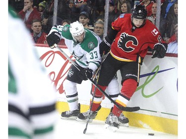 Joe Colborne of the Calgary Flames and Alex Goligoski of the Dallas Stars do battle along the boards in the Dallas zone during the first period at the Saddledome Friday night December 19, 2014.