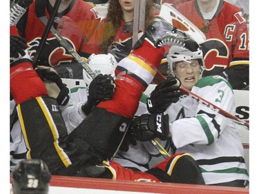 Lance Bouma of the Calgary Flames lands on the lap of John Klingberg, 3, and Cody Eakin afer getting knocked into the bench during the second period at the Saddledome Friday night December 19, 2014.