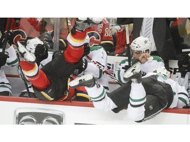 Lance Bouma of the Calgary Flames and Jyrki Jokipakka of the Dallas Stars crash into the Dallas bench simultaneously during the second period of Calgary's 2-1 loss, their 7th in a row, at the Saddledome Friday night December 19, 2014.