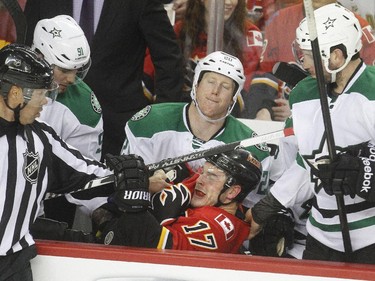 Lance Bouma of the Calgary Flames lands on the laps of Cody Eakin, centre, alongside Tyler Seguin, left, and Jason Demers, 4, after getting knocked into the bench during the second period at the Saddledome Friday night December 19, 2014.