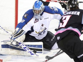 Kootenay Ice goalie Wyatt Hoflin, left, blocks a shot from Calgary Hitmen Kenton Helgesen during their game at the Scotiabank Saddledome on December 28, 2014.