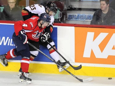 Calgary Hitmen left winger Taylor Sandheim got held up against the boards by Lethbridge Hurricanes defenceman Devan Fafard during WHL action at the Scotiabank Saddledome on December 30, 2014.