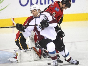 Former captain Jarome Iginla gets tied up by defenceman Dennis Wideman in front of Calgary Flames netminder Karri Ramo early in the first period  as he comes to the Saddledome with the Colorado Avalanche Thursday evening December 4, 2014.