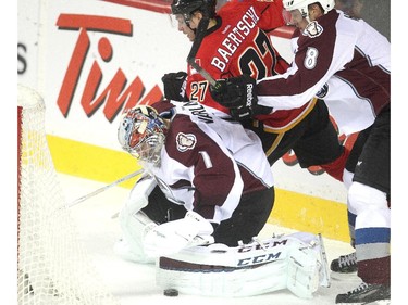 Sven Baertshci of the Calgary Flames nearly strips Colorado Avalanche goalie Semyon Varlamov of the puck behind the Colorado goal in the first period  at the Saddledome Thursday evening December 4, 2014. Defending on the play is Jan Hejda