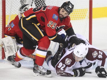 Brandon Bollig of the Calgary Flames knocks Gabriel Landeskog of the Colorado Avalanche to the ice in front of Calgary goalie Karri Ramo during the third period at the Saddledome Thursday evening December 4, 2014.