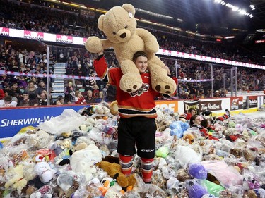 Calgary Hitmen Radel Fazleev jumps into a mound of teddy bears after scoring the first goal during the annual Teddy Bear toss game against the Moose Jaw Warriors at the Scotiabank Saddledome December 7, 2014.