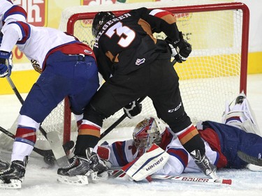 Calgary Hitmen left winger Kenton Helgesen tried to poke free the puck from Edmonton Oil Kings goalie Patrick Dea as Oil Kings defenceman Blake Orban tried to help during first period WHL action at the Scotiabank Saddledome on December 17, 2014.
