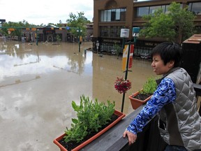 Stuart Gradon/Calgary Herald  CALGARY, AB: June 22, 2013 - Vin Room owner Phoebe Fung looks out on the flooded intersection of 4 St. and 24 Ave.S.W. from her business's rooftop patio in Mission in Calgary, Alberta Saturday, June 22, 2013. Vin Room's basement was still flooded.   (Stuart Gradon/Calgary Herald)  (For City story by TBA) 00046295C