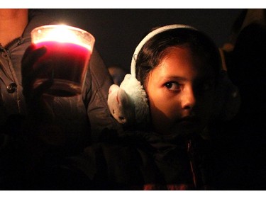 Divya Kaur, 7, looked at the candle she was holding as she joined her mom and dad along with a couple of hundred people as they gathered in an alley off Taracove Road NE near the site where a 17-year-old was abducted from and sexually assaulted last Friday night. The crowd gathered wearing glow sticks and carrying lights and candles to show their support for the victim and her family on November 20, 2014.