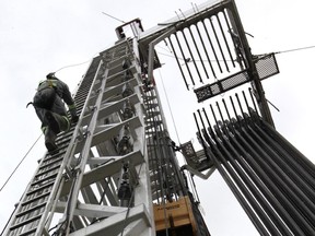 A Trinidad Drilling employee scales a rig working in Alberta. The company has cut its dividend to a penny to deal with lower activity.