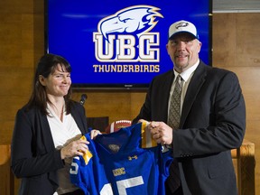 UBC football coach Blake Nill is presented with a jersey by Ashley Howard, Managing Director of UBC Athletics during a press conference introducing the new coach in Vancouver on Tuesday, a day after he resigned the same position with the University of Calgary Dinos.