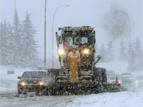 A snow plow chugs along 14th Street in slow-moving traffic. Reader says higher taxes would pay for better snow clearing.