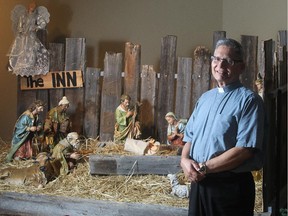 Father Julian Studden of St. Michael Catholic Church in Wentworth beside the church's nativity scene Wednesday December 17, 2014.