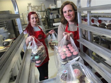 Jodi Willoughby, co-owner of the Crave cupcakes stores, right, along with staff member Laura Langille, put cupcakes on shelves at the Willow Park outlet Friday December 5, 2014. The day's unsold products are collected by the Calgary Food Bank.