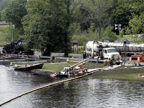 Workers using suction hoses try to clean up an oil spill of approximately 800,000 gallons of crude oil from the Kalamazoo River July 28, 2010 in Battle Creek, Mich.