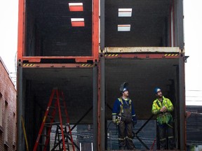 Workers look out from a shipping container on a lot where Canada's first multi-home recycled shipping container housing project that was being constructed in the Downtown Eastside of Vancouver, B.C., on Friday November 30, 2012. Twelve shipping containers were to be converted into 12 units of social and affordable housing for six elderly women paying $375 per month and six renters who will pay 30-percent of their gross income to a maximum of market rent. The Downtown Eastside of Vancouver is considered the poorest neighborhood in the country.