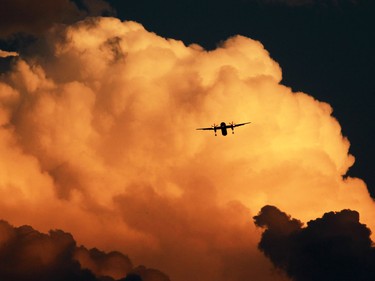 A forest fire fueled sunset and a thunder head provided a dramatic backdrop for a Dash 8 as it came into land at the Calgary International Airport on Wednesday evening July 16, 2014.