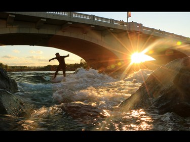 Jacob Kelly Quinlan surfs the wave close to the 10th Street bridge on Bow River on Wednesday evening August 27, 2014. The 2013 flood changed the river enough to create the new standing wave in the Bow.