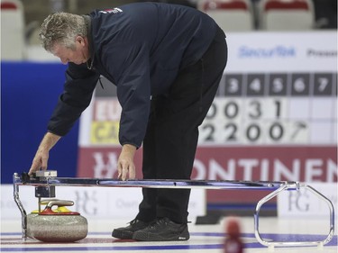 An official measures two rocks that are too close to call during mixed doubles Continental Cup action at the Markin MacPhail Centre in Calgary, on January 10, 2015. The final score was 8-5 for Team Canada.