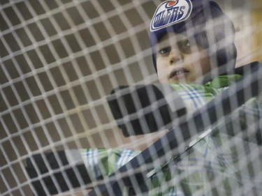 Emery Willms, 7, watches his brother Clark, who plays for the PeeWee league's Midnapore Mavericks, through the safety netting at the Max Bell arena on the first day of Esso Minor Hockey Week in Calgary, on January 10, 2015. The 36th annual EMHW will be held at rinks across the city from January 10 to 18, 2014.