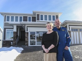 Andrea Robertson, left, STARS president and CEO, and Mike Janke, STARS pilot, pose in front of the 2015 STARS lottery Calgary grand prize show home in Crestmont.
