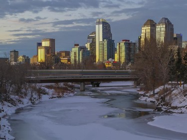 A sunset view of the Calgary downtown skyline, as the Ctrain crosses a bridge over the Elbow River.