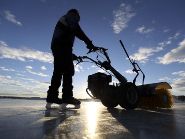 Billy Ritcher, a volunteer at Norm Prices 5-acre outdoor skating rink just east of Stony Trail, clears snow off the ice, in Calgary, on January 20, 2015.