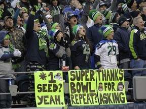 Seattle Seahawks fans cheer over signs predicting a second Super Bowl win for the Seattle Seahawks during the second half of an NFL football game against the St. Louis Rams, Sunday, Dec. 28, 2014, in Seattle. The Seahawks won 20-6 and will advance to the playoffs. (AP Photo/John Froschauer)