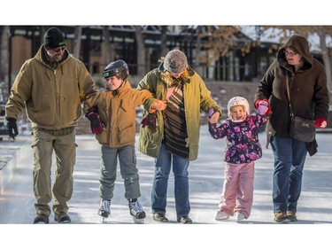 First time skaters, Duncan Harrison, 9, second from left, and his sister Ketta, 5, second from right, from Seattle, Washington, are guided by their dad Neil, left, mom Michelle, right, and their Calgarian aunt Andrea Thompson, centre, at the Olympic Plaza skating rink in Calgary, on December 30, 2014.